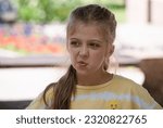 Small photo of The 10-year-old blond girl grimaced, showing disgust. Irony, disgust, whims. Phew! Cranky child, teenager.