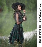 Small photo of Aristocratic dark-haired lady in a green dress on the shore of a pond