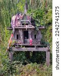 Small photo of A old wooden spirit house or Joss house built for guardian spirit to reside for protective spirit of a place On the overgrown grass beside the road. and Red soft drink is the belief of Thai villagers.