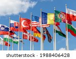 Group of flags of various states - as a symbol of world cooperation. Flags of the countries of the world on flagpoles flutter in the wind against the background of a blue sky