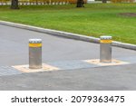 Two automatic security bollards on the asphalt road. Pillars for safe movement. Bollards with Security