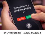 Smartphone user agrees to accept Terms of Service and Privacy Policy mobile app. Finger touches the Accept button. Dark app interface with Accept and Decline buttons