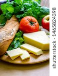 Small photo of A vertical shot of a delicious quick snack of a ploughman’s lunch with French bread mature cheese a fresh tomato and an apple.