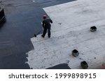 Waterproofing coating. A worker applies bitumen mastic to the foundation. Roofer cover the waterproofing primer on the roof, modified with polymer bitumen, with a roller brush.