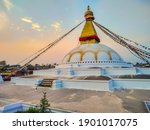 View of Boudhanath Stupa (or Bouddha Stupa) in the rays of the setting sun in Kathmandu city, Nepal. Prayer flags wings on the wind. No people. Religious architecture theme.