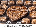 Small photo of Group of stamped Tula pryaniks (russian traditional gingerbread with honey or jam) lies on souvenir shop showcase. Russian text translation: "Tulsky" (from Tula) and "Tula delicacy". Soft focus.
