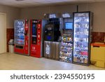 Small photo of Russia, Moscow - October 09, 2023: Special food zone: red coffee and snack vending machines, wooden micro market (small unattended store) and self-serve printer stands by wall. Soft focus.