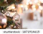 Christmas tree toy in the form of a house on a branch. Christmas mood background. Vacation atmosphere. Comfort hyuge concept cozy. Family budget Mortgage buying real estate