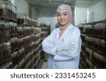Small photo of Portrait of young asian muslim female scientist doing research at a mushroom factory, examining mushroom leavening agent in a sterile and temperature-controlled room.