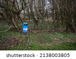 Small photo of Masham, Ripon, North Yorkshire. UK. 15th March 2022. Incongruous, this blue rubbish bin sits amongst trees on the banks of the River Ure at Masham