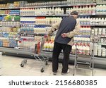Small photo of Moscow, Russia - 05.15.2022: Retired man with shopping cart stands by the shelves with milk products in a grocery store. Hyperinflation and inflation, milk products price increase. Economic crisis.
