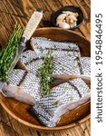 Small photo of Cut Raw grenadier macrurus white fish without head in a wooden plate. Wooden background. Top view