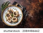 Small photo of Baked marrow veal beef bones in plate with thyme and herbs. Dark background. Top view. Copy space