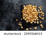 Homemade Crunchy Caramel Popcorn on marble board. Black background. Top view. Copy space