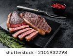 Grilled top sirloin or cup rump beef meat steak on marble board. Black background. Top view