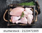 Fresh raw chicken meat and chicken parts - drumstick, breast fillet, wing, thigh. Black background. Top view