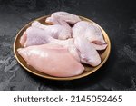 Fresh raw chicken meat with various parts - drumstick, breast fillet, wings, thigh. Black background. Top view.
