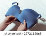 Woman holding blue bra, wooden background, closeup. Womens underwear.