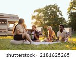 A group of college friends spend time together singing surrounded by nature. A bearded middle-aged boy plays the guitar. The good friends travel together in their beloved old camper van.