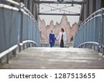 Women holding hands and walking across bridge