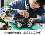 Small photo of Asian teenager students doing robot arm and robotic cars homework project in house disassemble the circuit and coding. technology of robotics programing and STEM education concept.