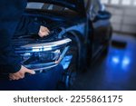 Small photo of Mechanic with new car headlight in a workshop