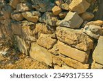 Small photo of Old wall, the foundation of stones, began to fall off due to the weathering of the mortar, adhering the stones together and cracks began to appear throughout the facade of the building. Concept of the
