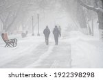 A snow-covered road with people in a storm,blizzard or snowfall in winter in bad weather in the city.Extreme winter weather conditions in the north.People walk through the streets under heavy snowfall