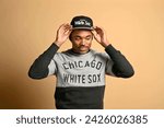 Small photo of Chicago, Illinois - February 15, 2024: A man adjusts his Chicago White Sox cap, paired with a coordinating team sweatshirt, showcasing his fan loyalty
