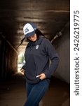 Small photo of Chicago, Illinois - February 15, 2024: A woman in a White Sox cap and hoodie exudes a casual, sporty vibe in an urban tunnel setting