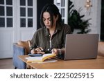 Pretty African American pretty student girl sitting at desk with laptop, diary uses calculator counts profit of her business. Remote working Brazilian young woman tired, feels fatigue.