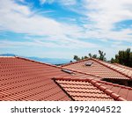 Modern house , red clay tiled roof, rain gutter and gable and valley type of roof construction. Roofing Construction.