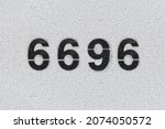 Small photo of Black Number 6696 on the white wall. Spray paint. Number six thousand six hundred ninety-six.