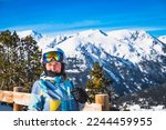 Portrait of young woman, looking at camera, with snowy Pyrenees Mountains in a background. Winter ski holidays in Andorra, El Tarter