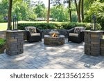 Small photo of A beautiful outdoors pavers with two comfortable armchairs and a fire pit in a natural green environment