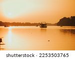 The Sava river between Bosnia and Croatia with boats floating on it under a bright golden sunset sky