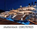 A row of luxury yachts docked in the marina at night.