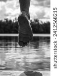 Small photo of Human foot on water surface in vertical grayscale