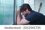 Small photo of Stressed man struggling with mental illness leaning by window suffering from emotional despair. One worried male person in 30s feeling pressure