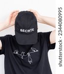 Small photo of A girl in a black baseball cap with the inscription infuriate and a black T-shirt with cats