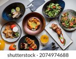 Set of various restaurant meals on gray background. Collage of different main courses, meat and fish dishes with garnish, salads and desserts, business lunch concept, top view