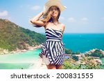 Young pretty woman posing at beautiful tropical island. Traveling in Koh Tao, Nang Yuan. Wearing stylish stripe black and white dress and retro hat.