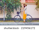 Outdoor fashion portrait of elegant lady riding her hipster retro bike in vintage stylish maxi skirt warm cardigan and straw hat. enjoy mica fall autumn day, posing at the street with birch trees.