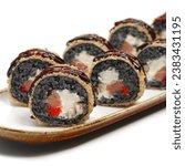 Small photo of Hot fried sushi rolls with salmon, eel, cheese and black rice. Tempura roll Black rice roll. Deep-fried sushi roll. Warm tempura maki roll on a white background. Close-up