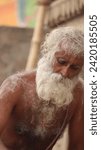 Small photo of Varanasi, Uttar Pradesh, India-Jan 18 2023: Close up portrait of an holy sadhu baba performing the rituals pooja at manikarnika ghat in kashi. White beard baba portrait unedited at the ghats, Banaras