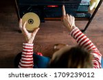 from above woman dressed in red striped t-shirt putting a compact disc or cd into a stereo in the interior of a house