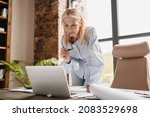Small photo of Concentrated caucasian middle-aged mature businesswoman ceo boss typing on laptop, working at office desk with documents, searching surfing web online