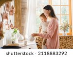 Small photo of Morning home breakfast. Motherhood moments. Adoption concept. Young mother nanny childminder babysitter holding embracing hugging little kid toddler newborn baby while drinking tea