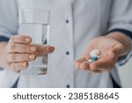 Small photo of Cropped shot of doctor hands giving pills and glass of water. Side effects of drugs. Aspirin, antidepressants, contraception, antibiotics closeup. Doctor`s prescription treatment. Pharmacology