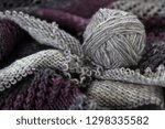 Small photo of A ball of grey yarn or wool resting on knitting showing different stictches and textures. Crafting, knitting, make do and mend, hand craft concepts.